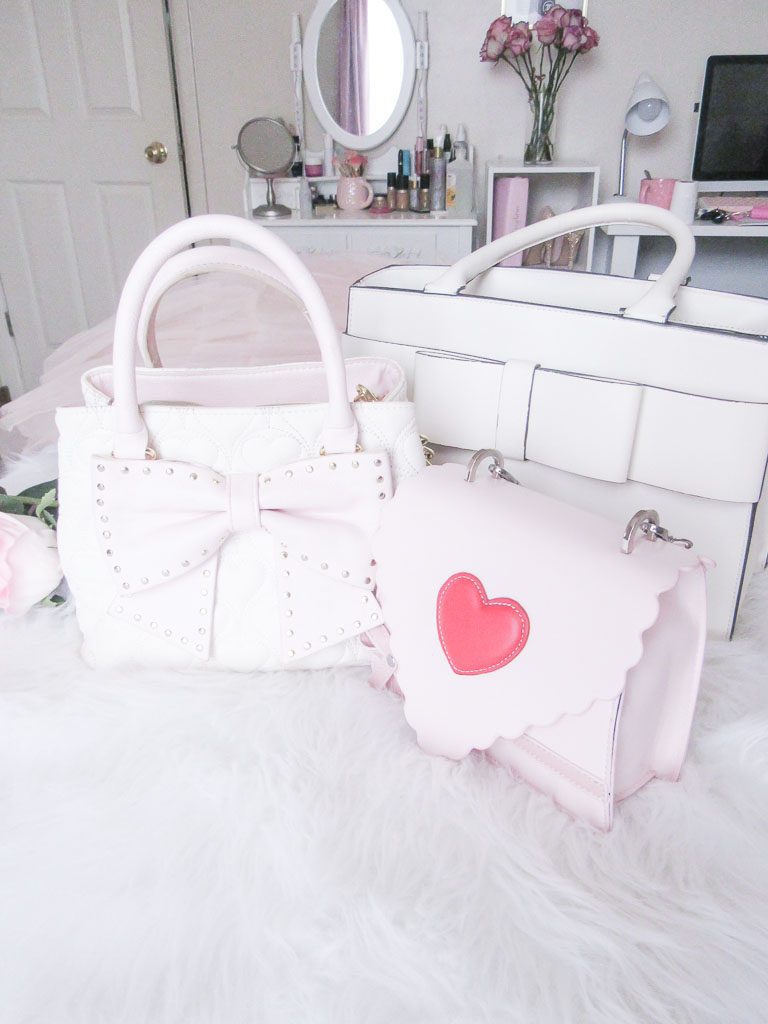Pink and white handbags on a white bed.
